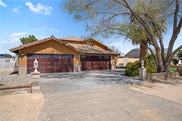 view of front of house with stucco siding, a garage, driveway, and fence