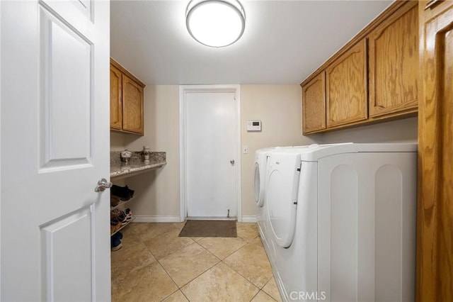 laundry area with baseboards, cabinet space, washing machine and dryer, and light tile patterned flooring