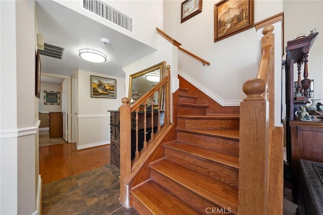 staircase featuring visible vents, baseboards, and wood finished floors
