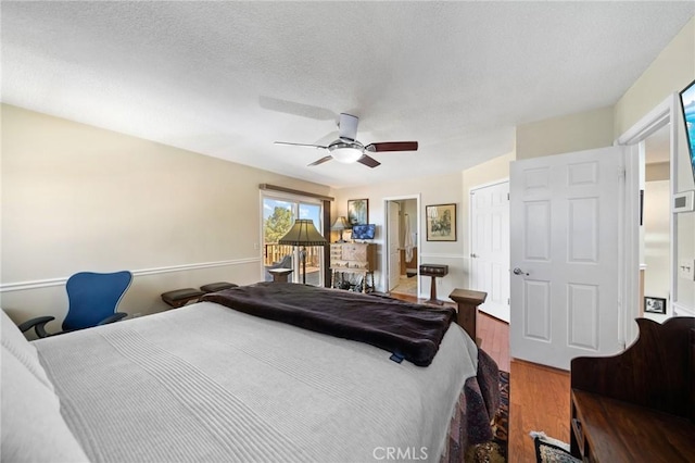 bedroom with access to exterior, ceiling fan, wood finished floors, a closet, and a textured ceiling
