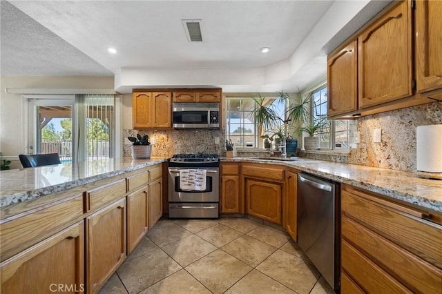 kitchen featuring a sink, brown cabinetry, visible vents, and stainless steel appliances