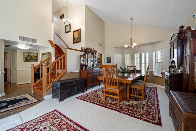 dining room with visible vents, high vaulted ceiling, baseboards, a chandelier, and stairs