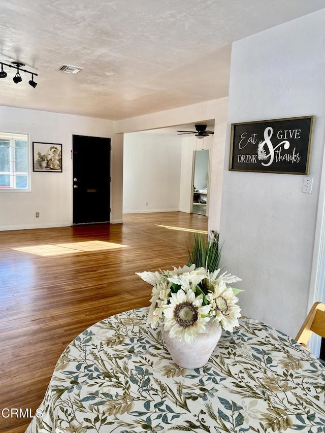 interior space featuring visible vents, baseboards, ceiling fan, and wood finished floors
