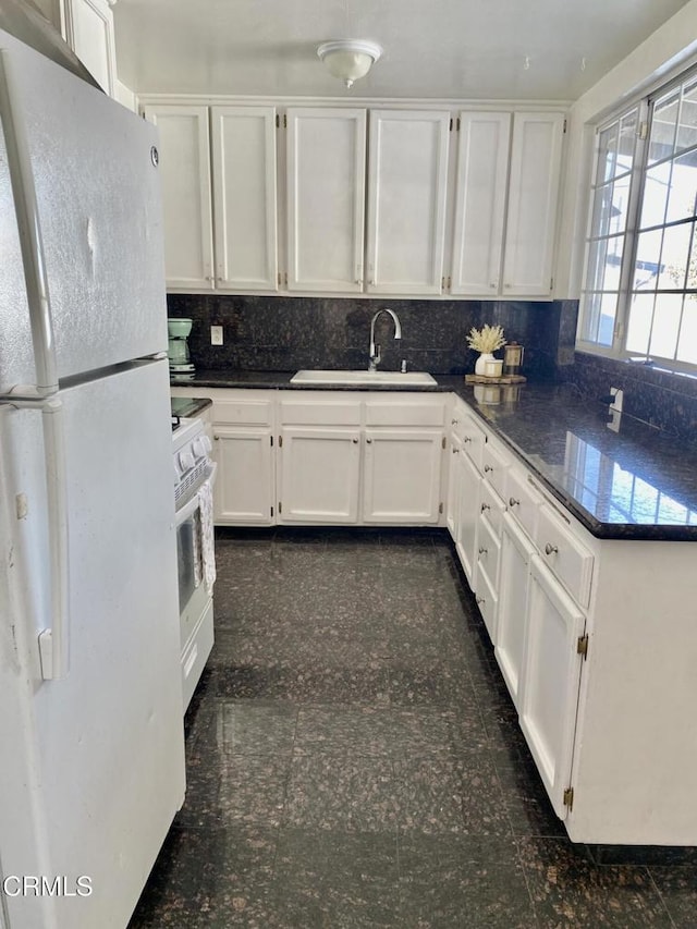 kitchen with a sink, backsplash, white cabinetry, granite finish floor, and white appliances