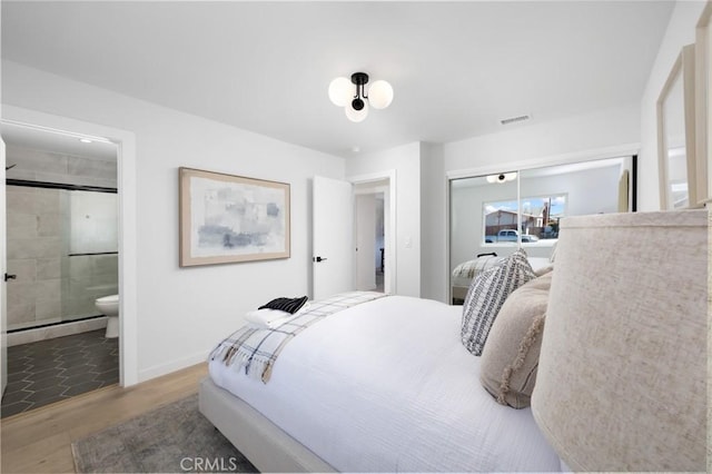 bedroom featuring visible vents, a closet, wood finished floors, baseboards, and a baseboard radiator