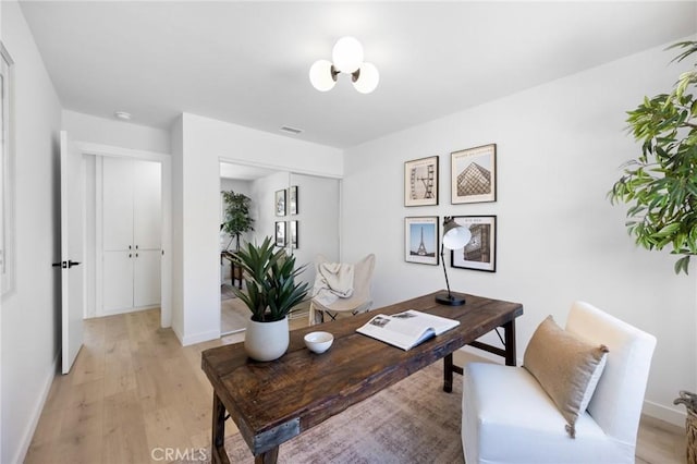 office space with baseboards, light wood finished floors, and visible vents