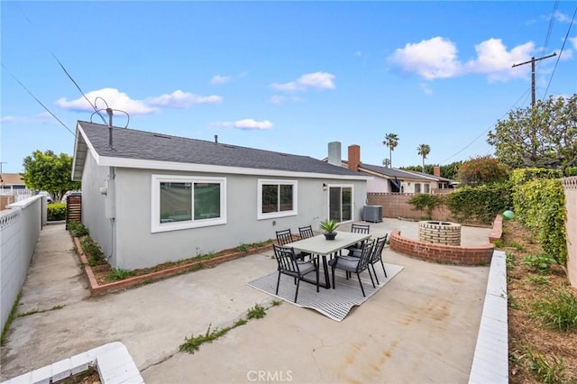 rear view of house with a fenced backyard, a patio, stucco siding, and an outdoor fire pit