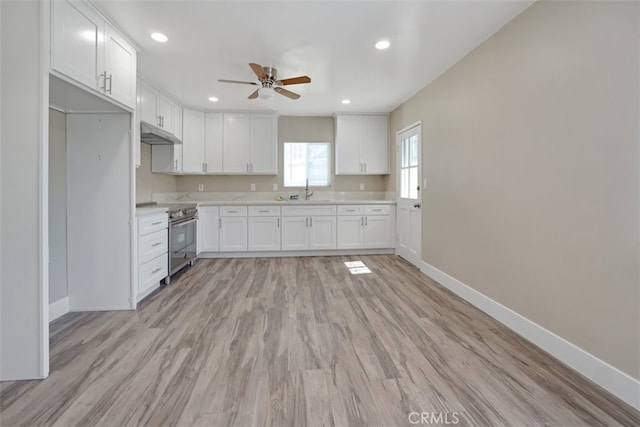 kitchen with under cabinet range hood, light countertops, stainless steel electric range oven, baseboards, and ceiling fan