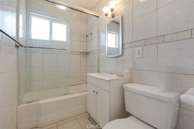 full bathroom with bath / shower combo with glass door, toilet, vanity, tile patterned floors, and tile walls