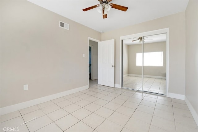 unfurnished bedroom featuring visible vents, baseboards, light tile patterned floors, a closet, and a ceiling fan