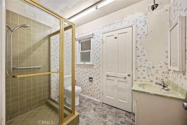 bathroom featuring a shower stall, wallpapered walls, vanity, and toilet