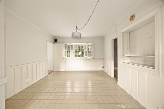 spare room featuring a wainscoted wall and crown molding