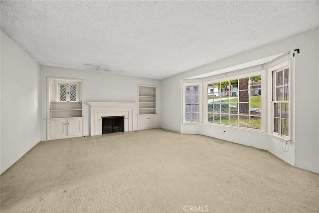 unfurnished living room with a fireplace with flush hearth, carpet floors, and a textured ceiling