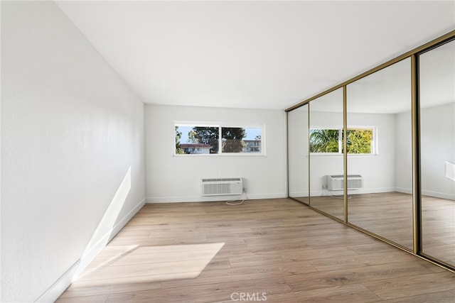 2392 Via Mariposa W Unit 3D, Laguna Woods, CA 92637 - unfurnished bedroom with multiple windows, a wall unit AC, wood finished floors, and a closet