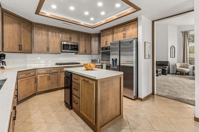 kitchen with light countertops, a tray ceiling, light tile patterned floors, stainless steel appliances, and a toaster