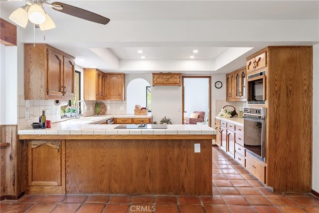 13155 San Antonio Rd, Atascadero, CA 93422 - kitchen featuring appliances with stainless steel finishes, a raised ceiling, a peninsula, brown cabinets, and recessed lighting