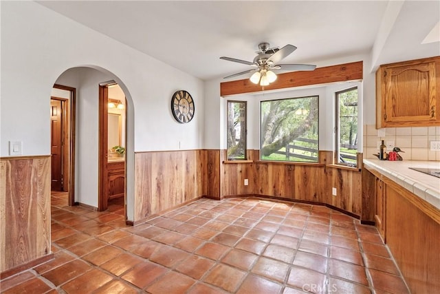 13155 San Antonio Rd, Atascadero, CA 93422 - unfurnished dining area featuring wainscoting, wooden walls, ceiling fan, arched walkways, and vaulted ceiling