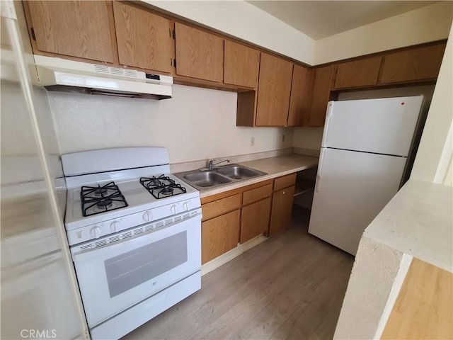 kitchen featuring white appliances, a sink, light countertops, light wood-style floors, and under cabinet range hood