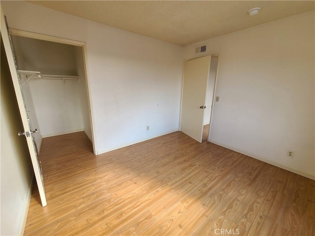 unfurnished bedroom with a closet, visible vents, baseboards, and light wood-style floors