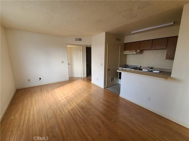 unfurnished living room featuring visible vents, a textured ceiling, and wood finished floors
