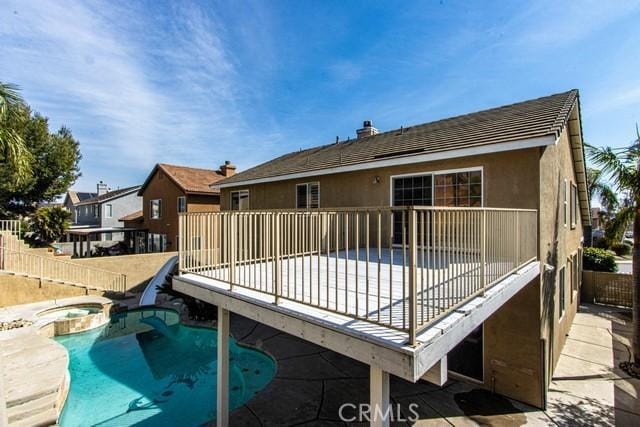 back of house featuring stucco siding, a residential view, fence, and a pool with connected hot tub