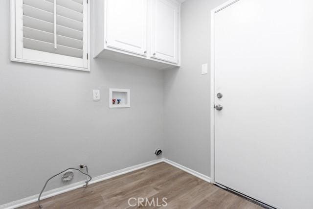 washroom with washer hookup, wood finished floors, cabinet space, and baseboards