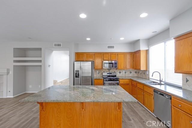 kitchen featuring visible vents, a sink, a center island, stainless steel appliances, and light wood-style floors
