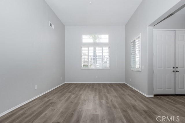 spare room with wood finished floors, visible vents, and baseboards