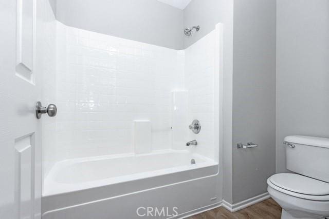 bathroom with toilet, bathing tub / shower combination, baseboards, and wood finished floors