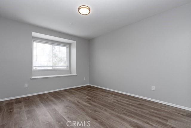 unfurnished room with baseboards and dark wood finished floors