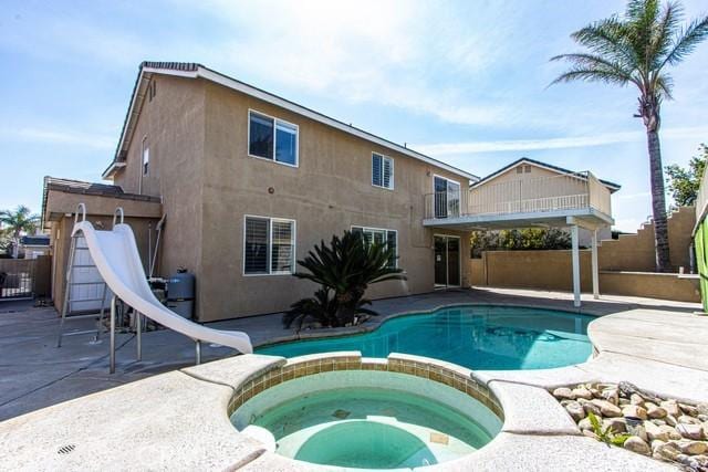 view of pool with a pool with connected hot tub, a patio area, fence, and a water slide