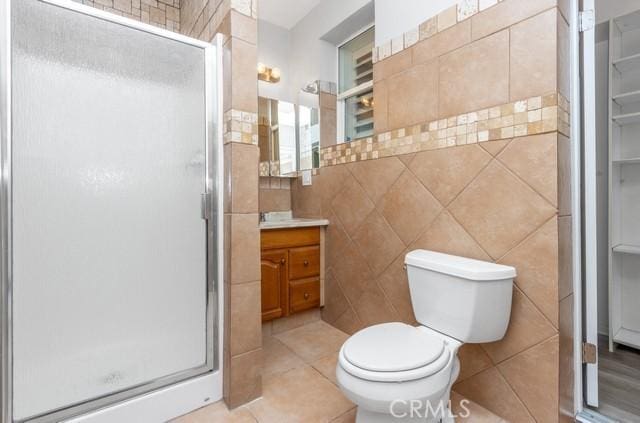 full bath featuring vanity, tile walls, toilet, and a stall shower