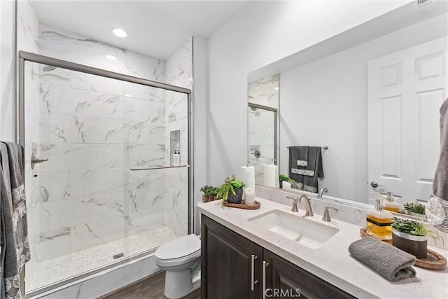 full bathroom with wood finished floors, toilet, vanity, and a marble finish shower