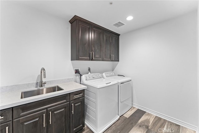 laundry room with a sink, dark wood-style flooring, visible vents, separate washer and dryer, and cabinet space