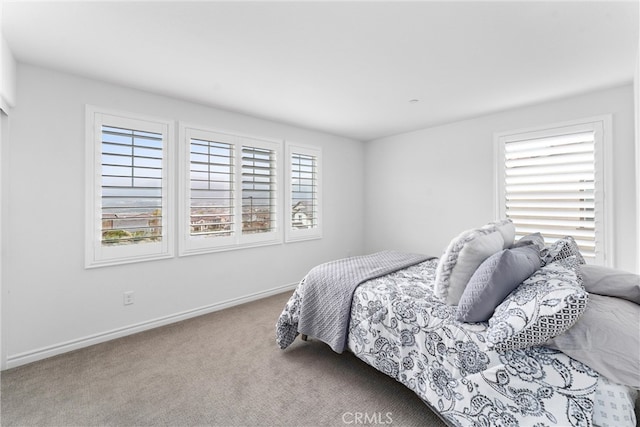 bedroom featuring baseboards, carpet flooring, and multiple windows