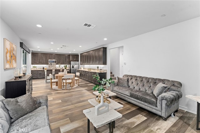 living room featuring light wood finished floors, visible vents, and recessed lighting