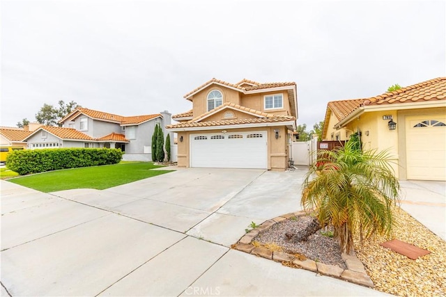 mediterranean / spanish home with a tiled roof, a gate, stucco siding, and driveway