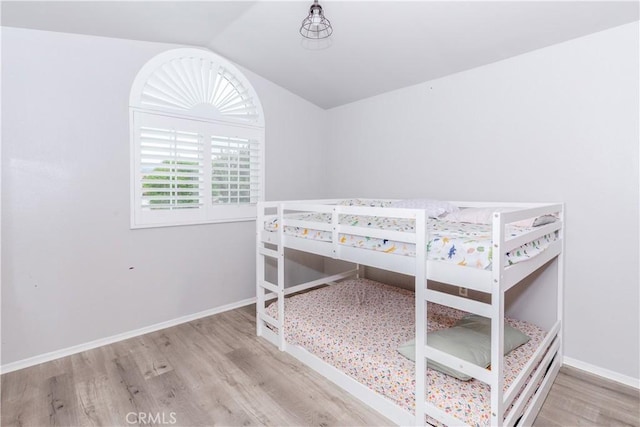bedroom with baseboards, wood finished floors, and lofted ceiling