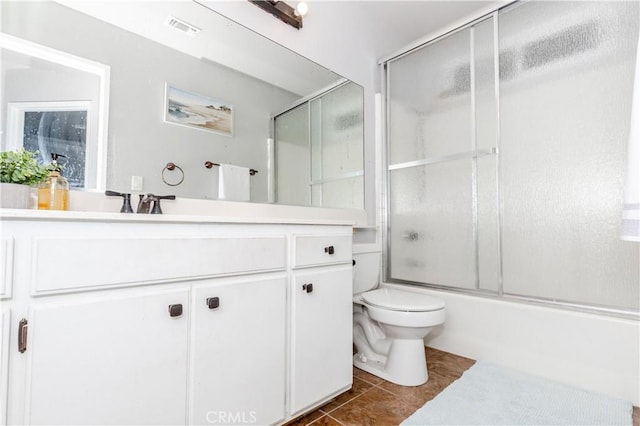bathroom with visible vents, vanity, toilet, tile patterned floors, and enclosed tub / shower combo