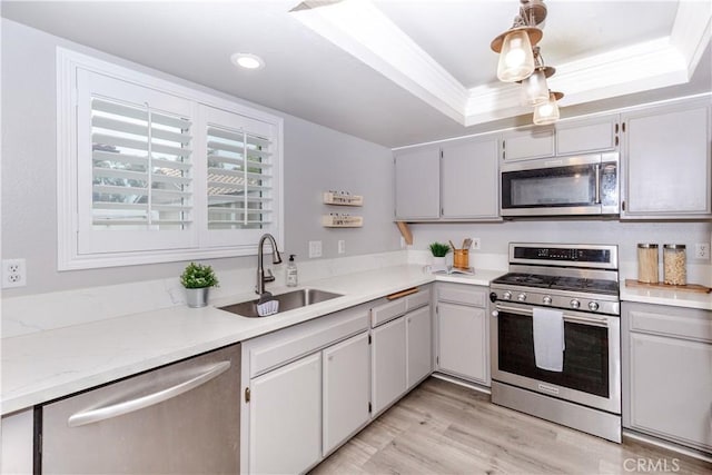 kitchen featuring a sink, a raised ceiling, light countertops, stainless steel appliances, and recessed lighting