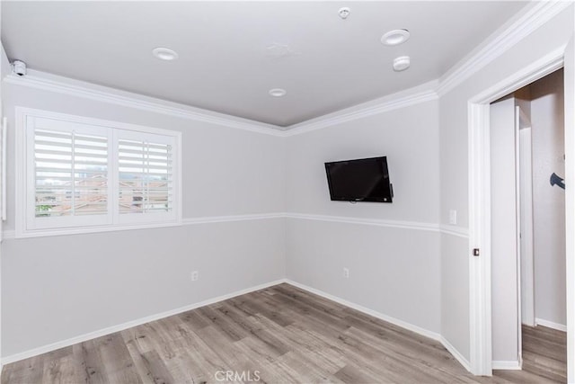 empty room featuring baseboards, ornamental molding, and wood finished floors