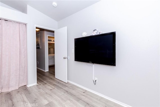 unfurnished bedroom featuring a closet, baseboards, vaulted ceiling, and wood finished floors