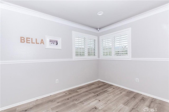 spare room featuring crown molding, baseboards, and wood finished floors