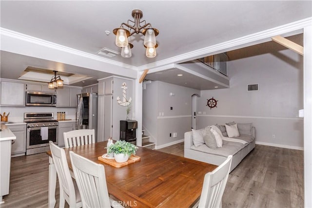 dining room with visible vents, stairs, wood finished floors, and a chandelier