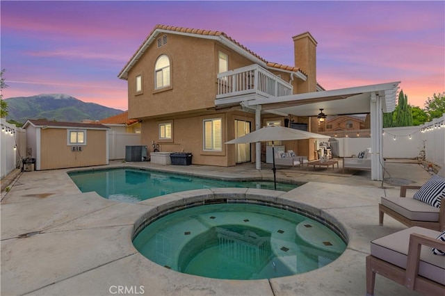 back of property at dusk featuring a fenced backyard, cooling unit, a patio area, and a balcony