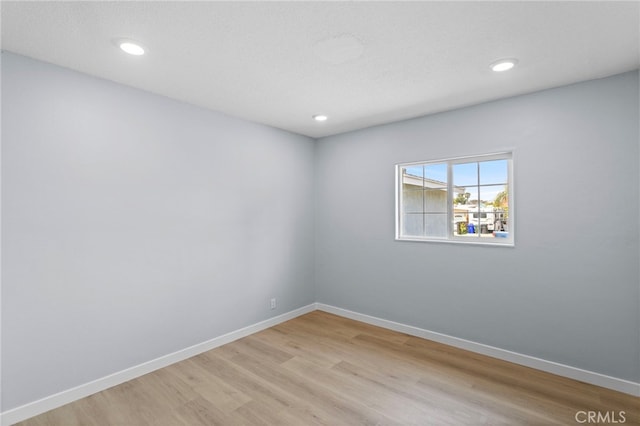 spare room with light wood finished floors, baseboards, and recessed lighting