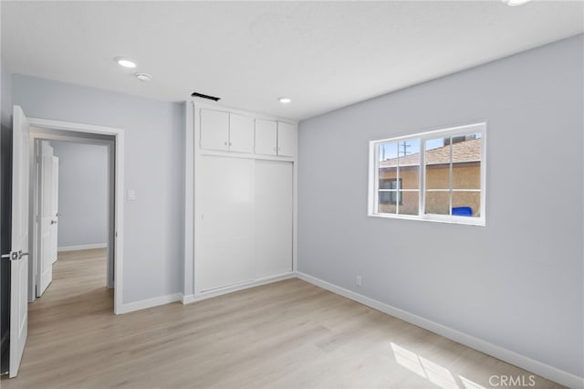 unfurnished bedroom featuring a closet, baseboards, recessed lighting, light wood-style floors, and visible vents