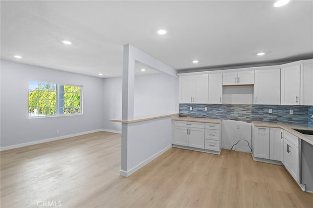 kitchen with light wood finished floors, baseboards, and backsplash