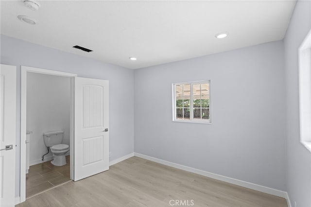 unfurnished bedroom featuring baseboards, recessed lighting, ensuite bath, light wood-style flooring, and visible vents