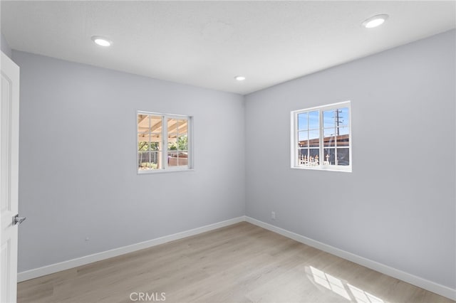 empty room with baseboards, light wood-type flooring, and recessed lighting